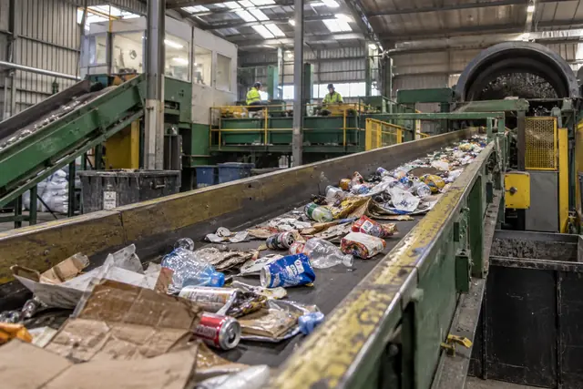 Mixed recyclables, cans, bottles and cardboard, on a sorting line conveyor in a materials recovery facility